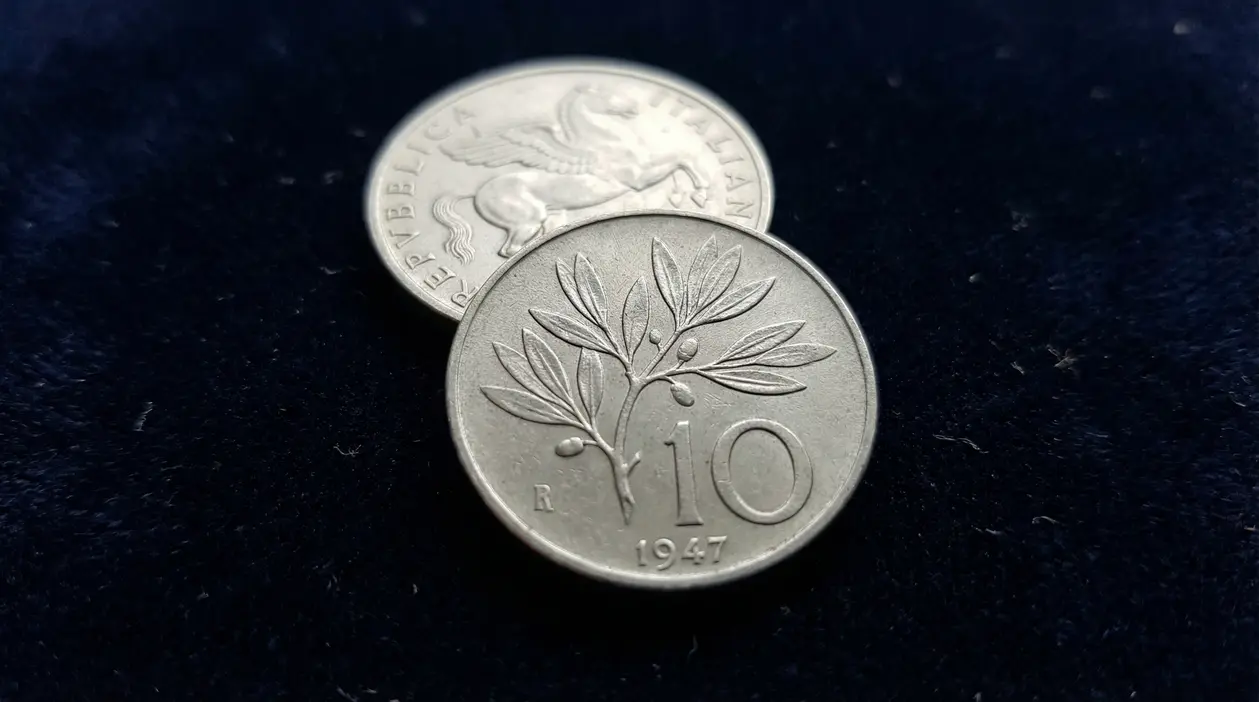 Moneta da 10 lire del 1947 su sfondo scuro, con ramo d'ulivo inciso
