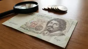 Banconota da 100.000 lire con ritratto di Caravaggio, firma Fazio e lente d’ingrandimento
