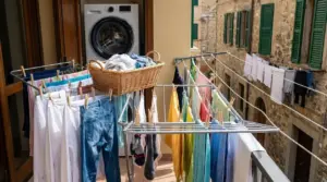 Bucato steso sul balcone con stendino, mollette e cestino, per asciugare i capi riducendo le pieghe