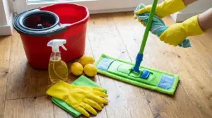Mocio su pavimento in legno con secchio, guanti e limoni per igienizzare i pavimenti con rimedi naturali