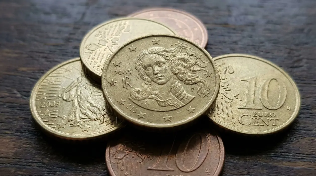 Monete da 10 centesimi di euro sparse su una superficie in legno