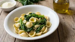 Piatto di orecchiette con cime di rapa su tavolo di legno