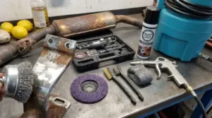 Attrezzi e pezzo di metallo arrugginito su banco da lavoro per pulire il metallo e rimuovere la ruggine