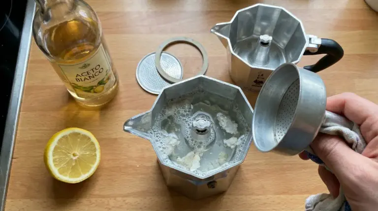 Moka smontata con residui di calcare, aceto bianco e limone su un piano da cucina