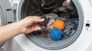 Mano che rimuove peli dalla lavatrice con panni e palline cattura-peli nel cestello