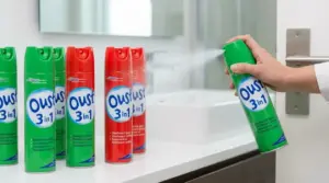 Mano che spruzza uno spray disinfettante in bagno, con bombolette di detergente sul lavandino