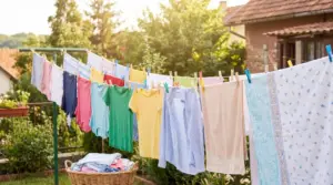 Panni stesi al sole su fili da bucato in giardino, con magliette e asciugamani all’aperto