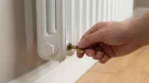 Mano che usa una chiave per sfiatare un termosifone bianco, per eliminare l’aria e farlo scaldare meglio